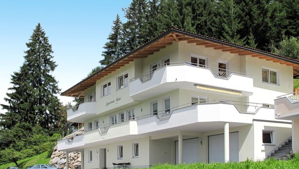 Um edifício de vários andares com fachada branca, varandas e uma placa com a inscrição