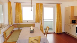 Uma área de jantar com uma mesa posta para quatro, um banco e vista para a varanda através da janela.