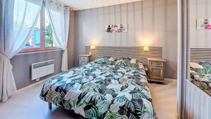 A bedroom with a bed, bedside tables, a radiator, a window with curtains, a wall-mounted shelf, and a ceiling light fixture. - Tuilières by Interhome (Pauillac)