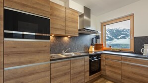Una cocina moderna con armarios de madera, un lavamanos de acero inoxidable y una ventana con vistas a la montaña.
