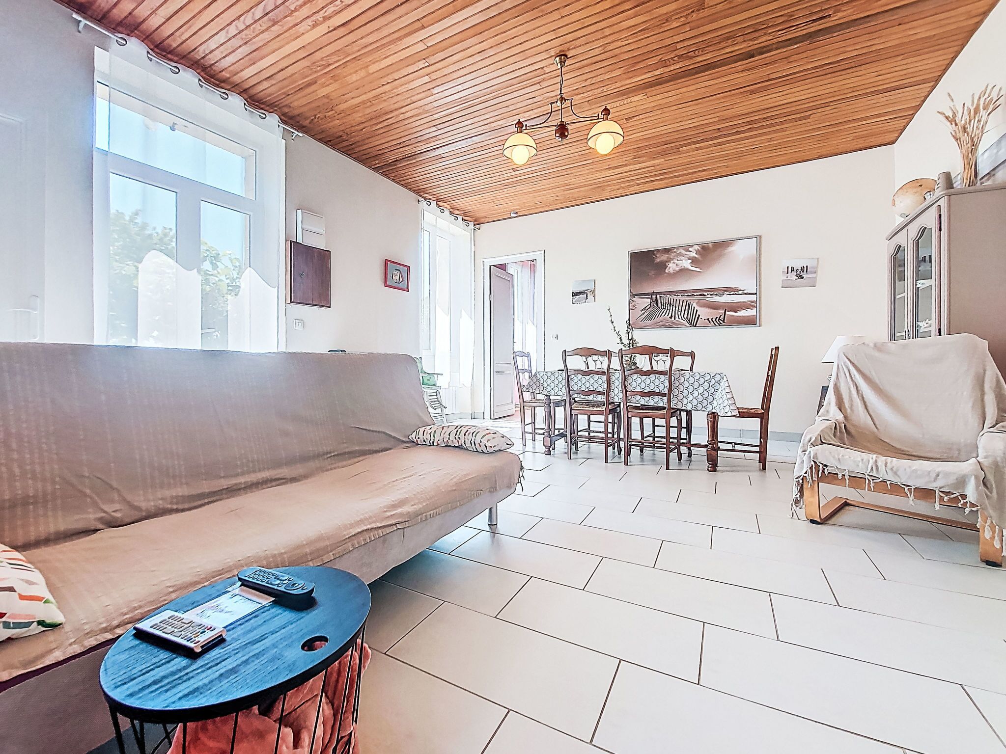 Una sala de estar acogedora con techo de madera, un sofá, una mesita redonda y un comedor con sillas y una mesa.