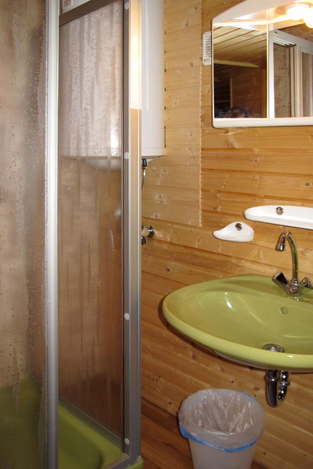 Un baño con cabina de ducha, lavabo y espejo.