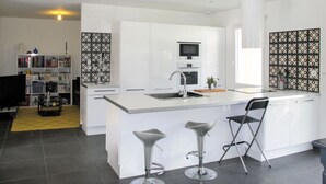 Eine moderne Küche mit einer zentralen Kochinsel, Barhocker und einem eingebauten Backofen.