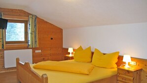 A wooden bed with yellow bedding in a room with wooden walls and a window. - Unterkreuter by Interhome (Kaltenbach)