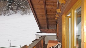 A wooden balcony with a table and chairs, overlooking a snowy landscape. - Unterkreuter by Interhome (Kaltenbach)