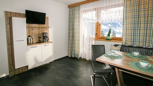 Kompakti keittiö, jossa on sisäänrakennettu televisio, kahvinkeitin ja ikkuna, josta avautuu näkymä vuorille.