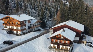 Une zone montagneuse enneigée avec deux bâtiments en bois, dont l’un possède un balcon et l’autre une grande véranda.