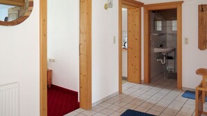 Un couloir avec des portes en bois donnant accès à une salle de bain et à une cuisine.