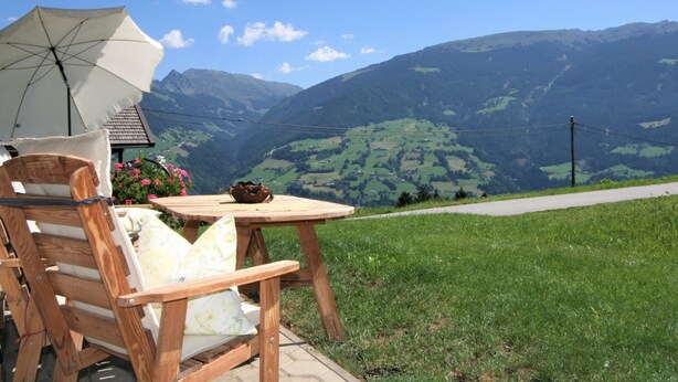 Un juego de mesa y sillas de madera al aire libre, con vista a la montaña.