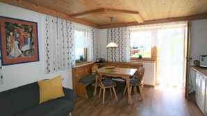 Una habitación acogedora con techo de madera, una mesa de comedor con sillas, un sofá y una ventana con cortinas.