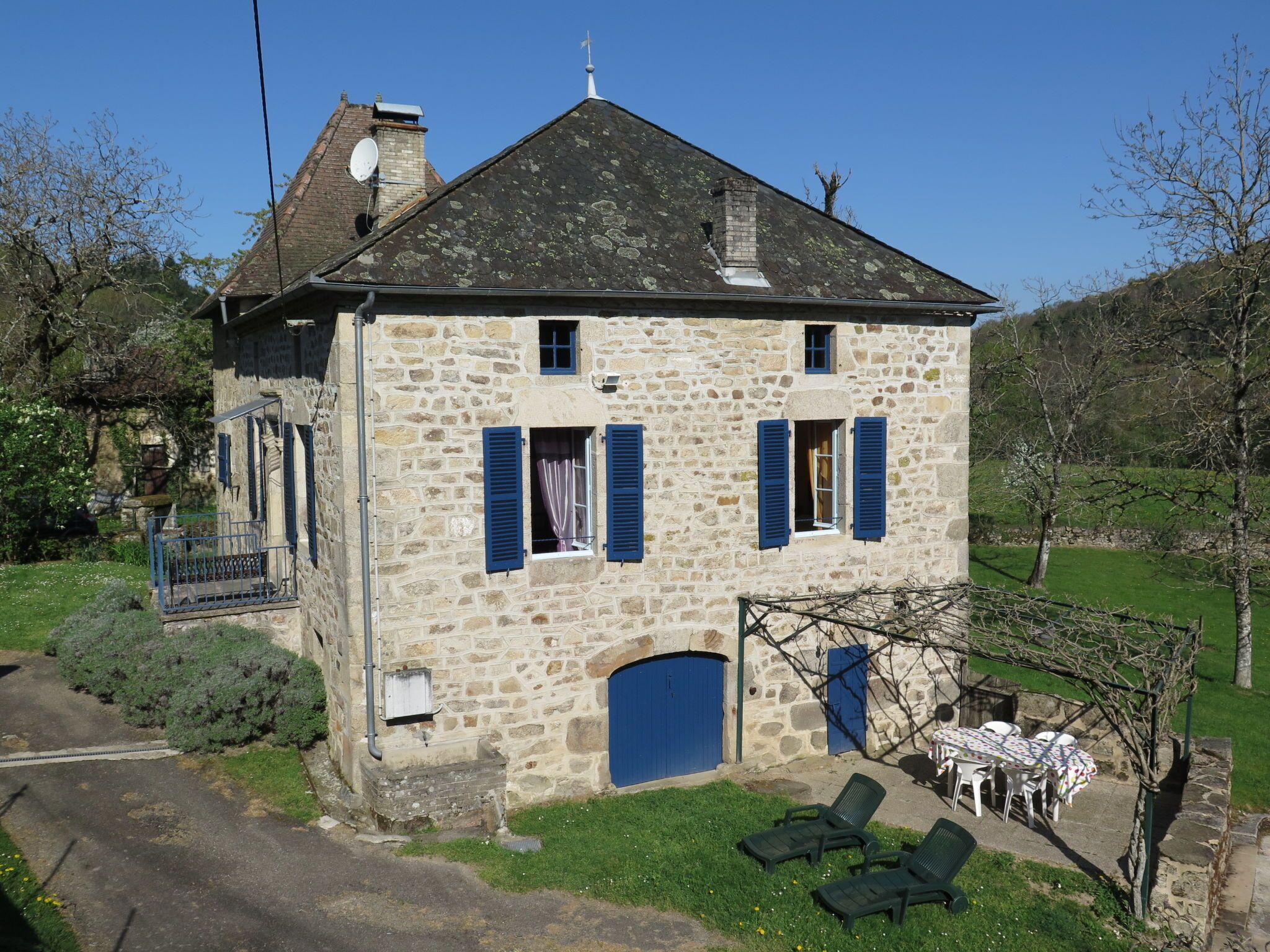 A stone building with a balcony, a door, and a small garden area with a table and chairs.