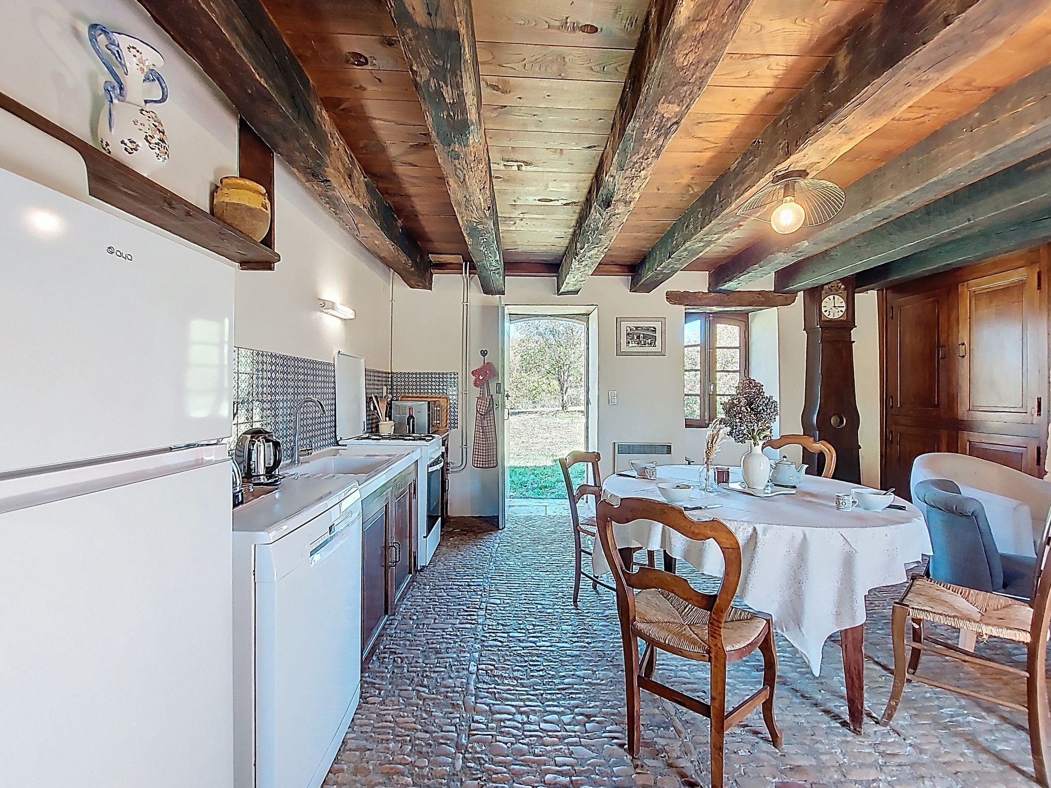 Una cucina rustica con pavimento in pietra, travi in legno e zona pranzo con tavolo e sedie.