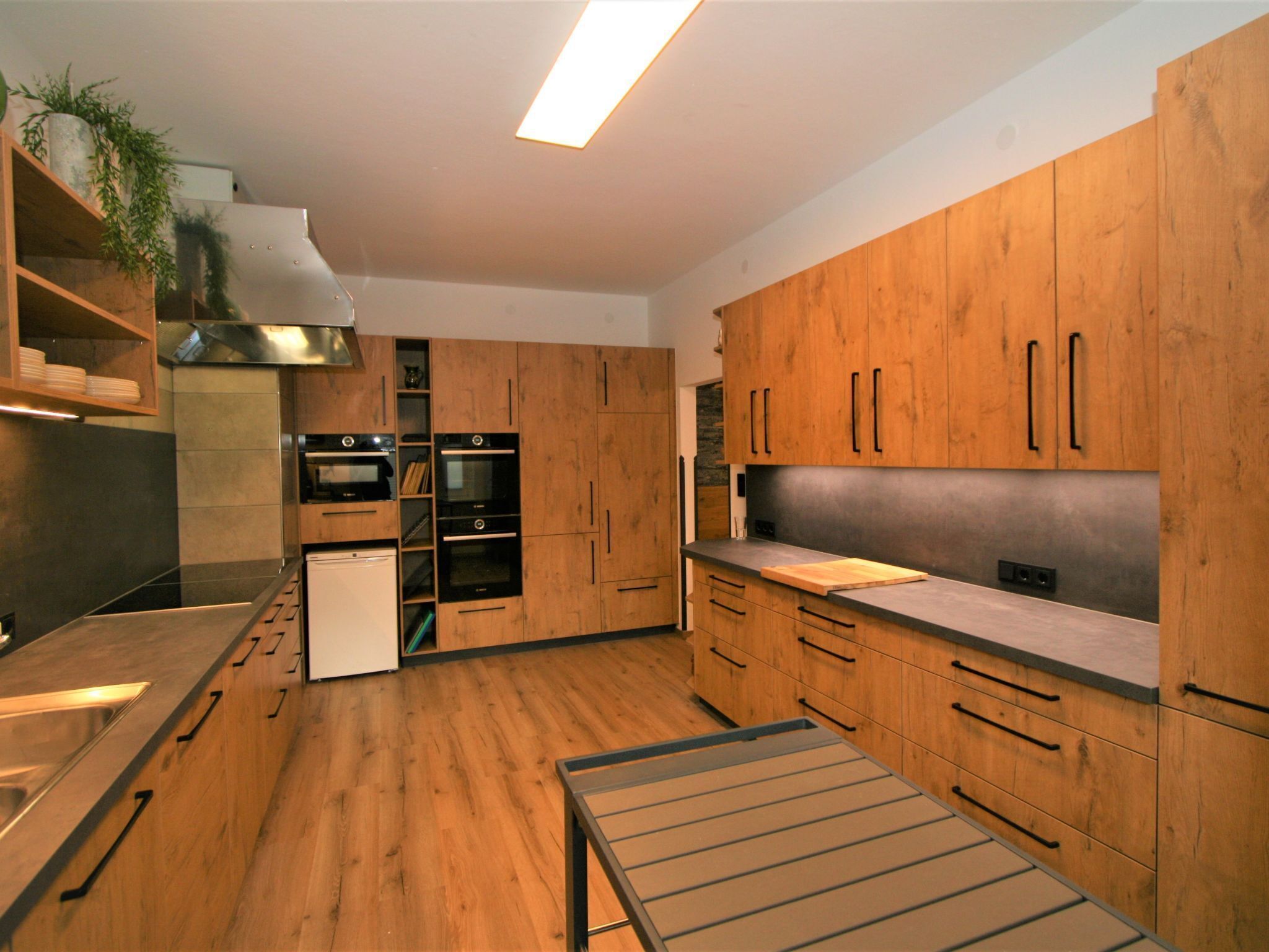 Eine moderne Küche mit Holzausstattung, Edelstahlgeräten und einem eingebauten Backofen.