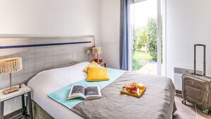 Une chambre d’hôtel avec un lit, des lampes de chevet, une valise et un plateau de petit-déjeuner.