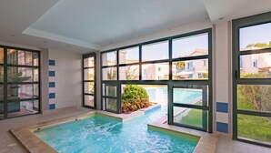 Une piscine donnant sur un quartier résidentiel grâce à de grandes baies vitrées.