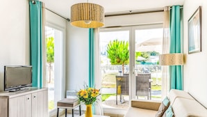 Un salon moderne avec un canapé, un téléviseur, une table basse et une vue sur l’extérieur.