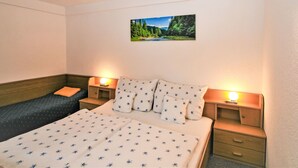 Une chambre à coucher comprenant un lit, deux tables de chevet, une commode, un banc et un tableau accroché au mur.