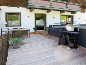 Une terrasse en bois avec des meubles d’extérieur et un espace barbecue.
