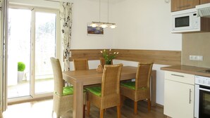 A modern kitchen with a dining table, wicker chairs, a microwave, and a stove. - Apartment Wurm by Interhome (Fügen)