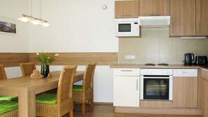 A compact kitchen with a dining area, featuring a microwave, oven, and dishwasher. - Apartment Wurm by Interhome (Fügen)