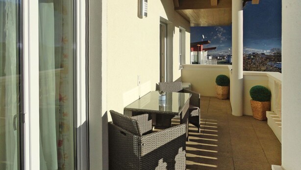 A balcony with wicker furniture, a glass table, and potted plants. - Apartment Wurm by Interhome (Fügen)
