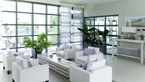 Ein modernes Wohnzimmer mit weißen Sofas, einem Couchtisch und großen Fenstern mit Blick ins Freie.