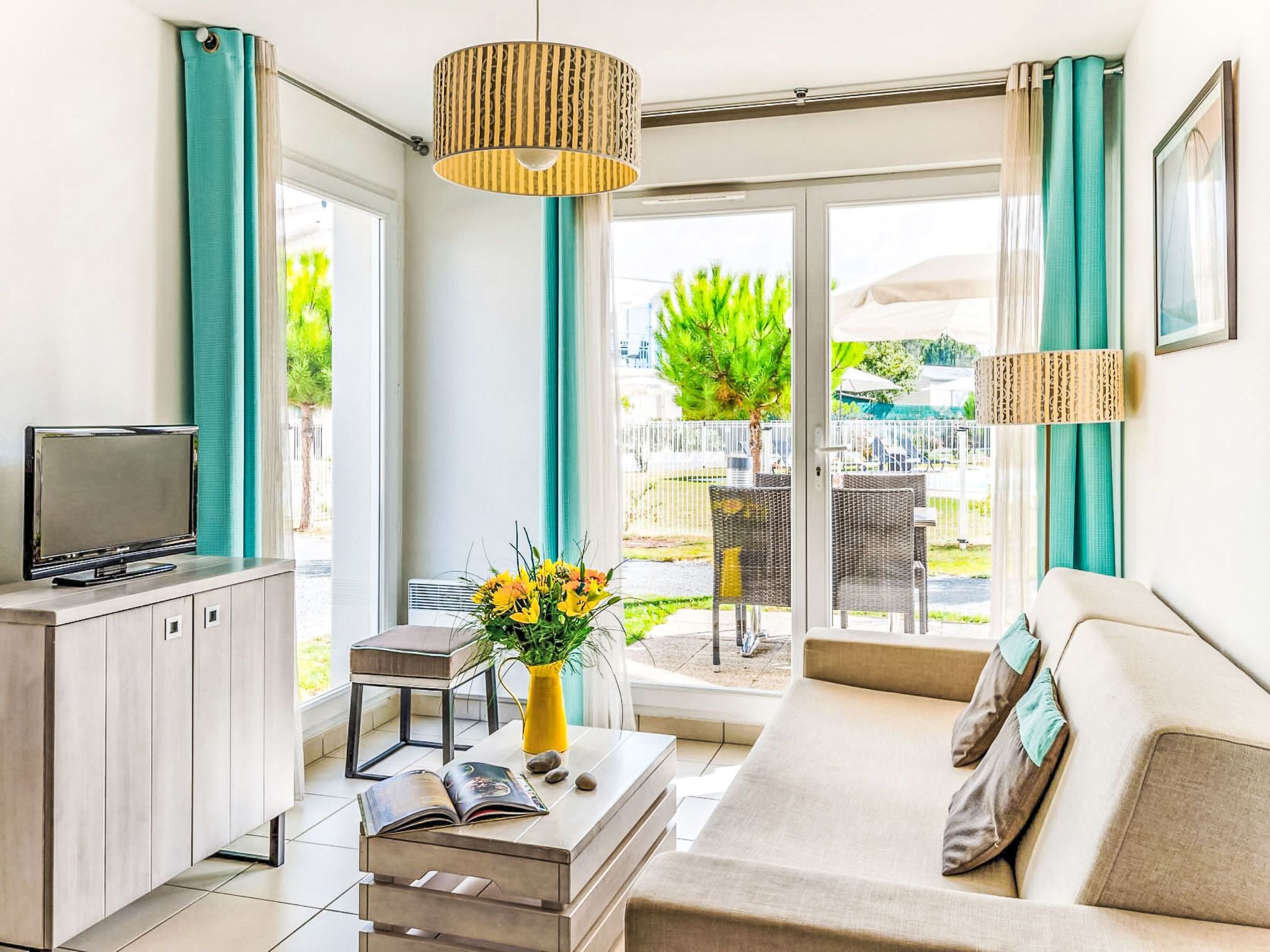 A modern living room with a sofa, a TV, a coffee table, and a view of the outside.