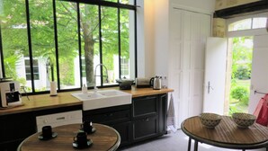 Ett modernt kök med ett stort fönster, en diskho, en kaffemaskin och ett litet matbord.
