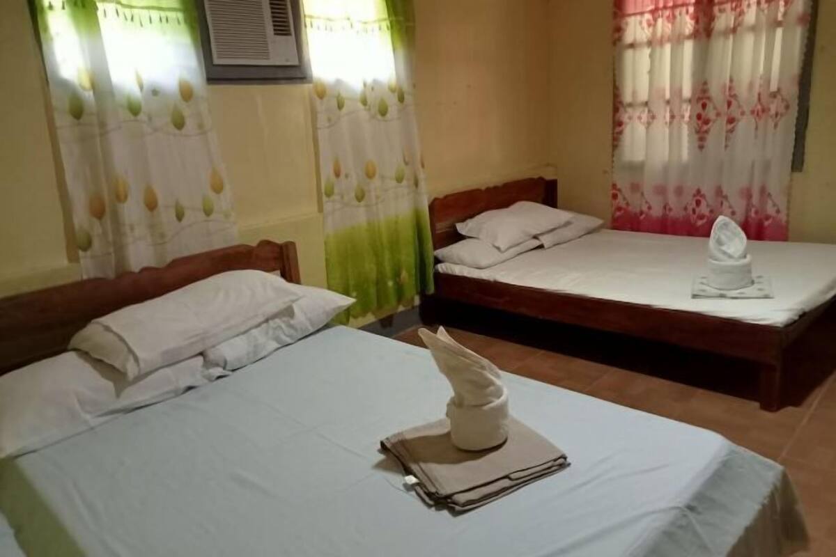 A hotel room with two beds, each with white linens and pillows, and a neatly folded towel on one bed.