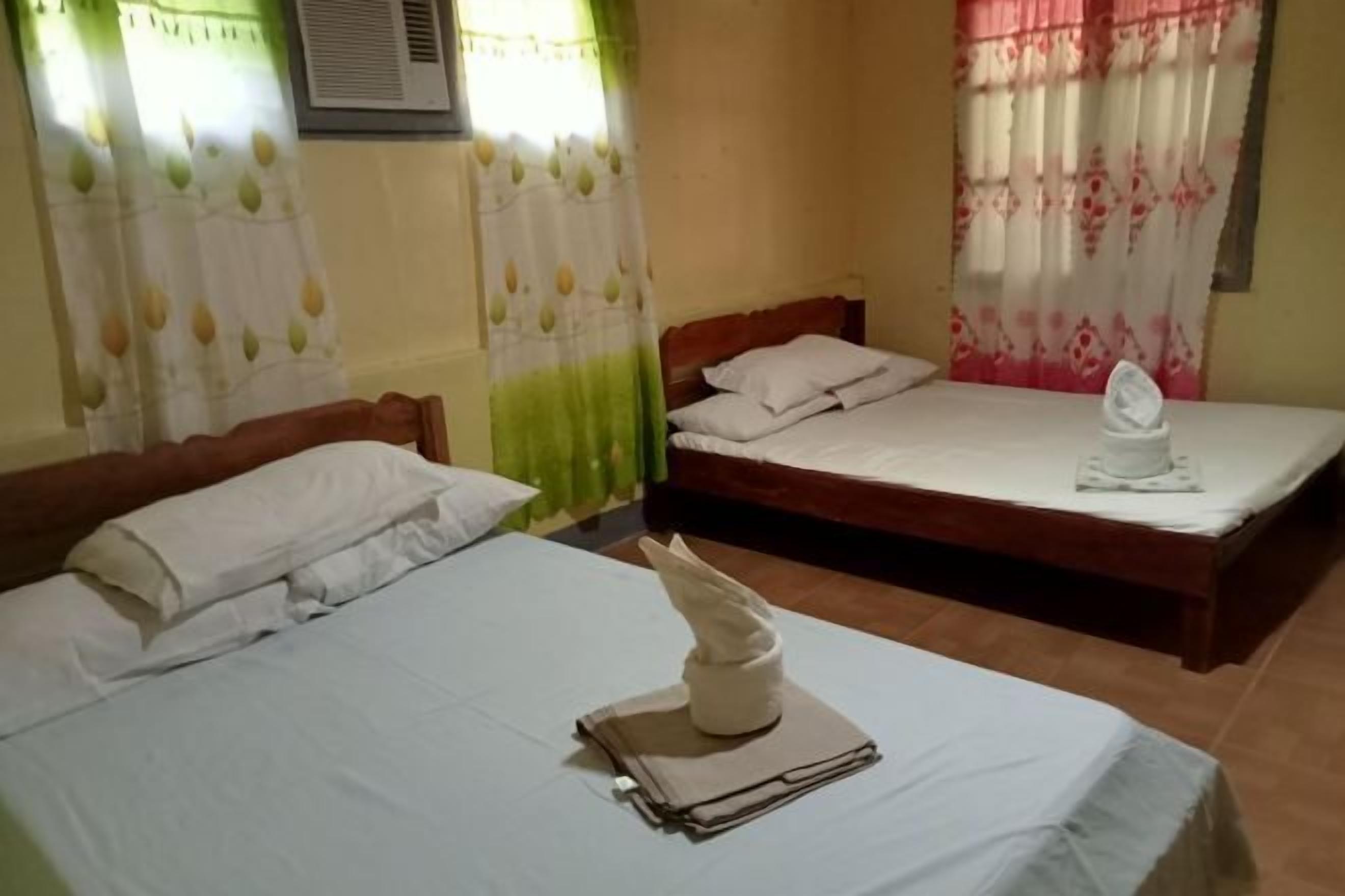 Ein Hotelzimmer mit zwei Betten, einem Fenster mit Vorhängen und einer Klimaanlage.