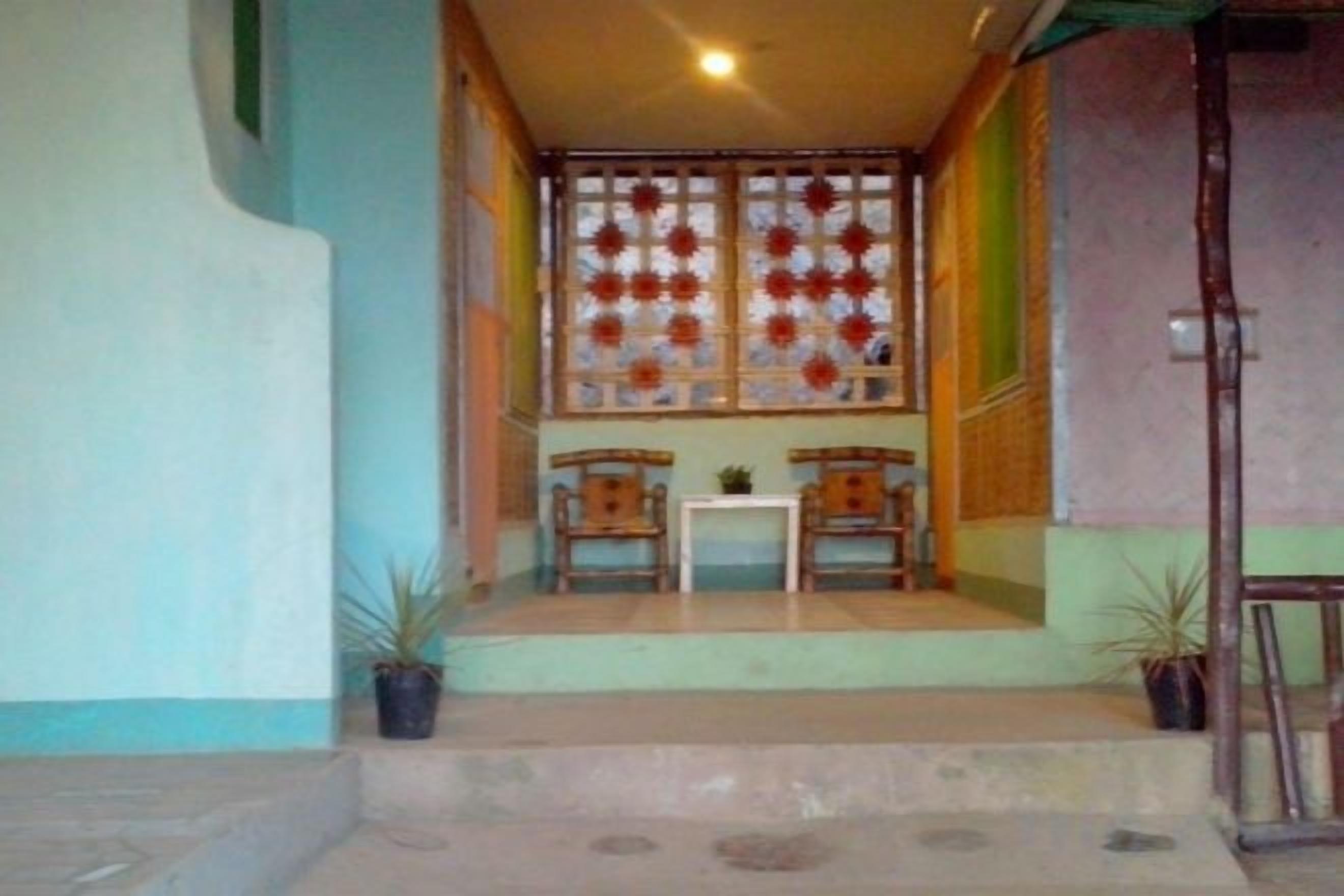 A room with a window, a small table, two chairs, and a potted plant.