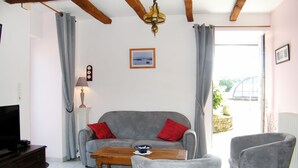 Una sala de estar con un sofá gris, dos cojines rojos, una mesa de centro de madera y sillones grises.