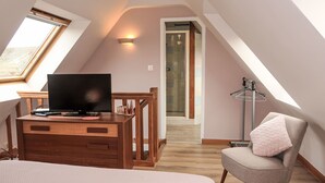 A bedroom with a bed, a desk with a TV, a chair, a wardrobe, and a skylight. - L'Hirondelle by Interhome (Saint Jean du Doigt)