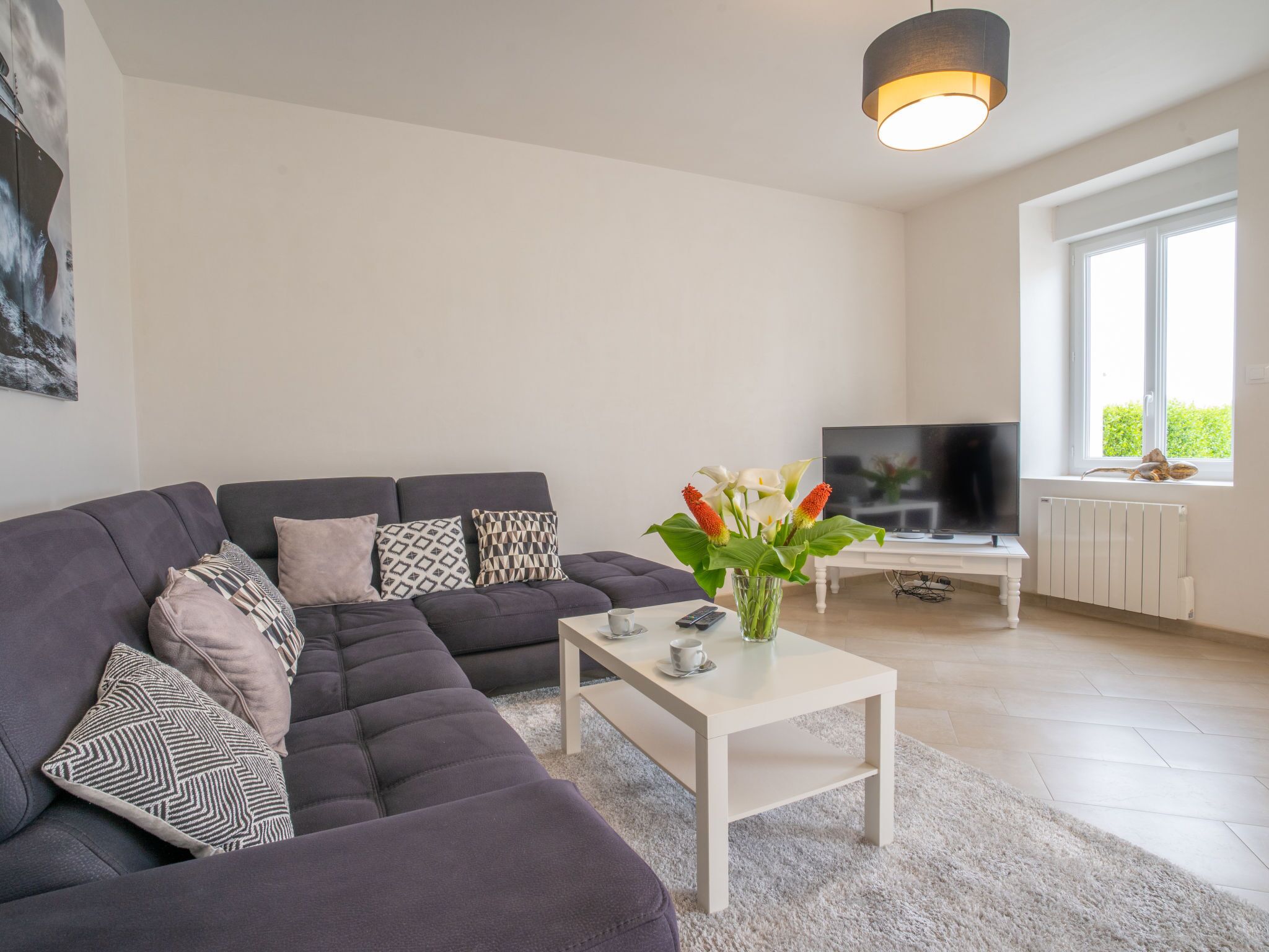 Ein modernes Wohnzimmer mit einer Eckcouch, einem Couchtisch, einem Fernseher und einem Fenster mit Blick.