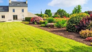 A two-story house with a well-maintained lawn and colorful garden beds. - L'Oasis by Interhome (Plouneour Trez)