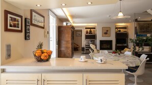 Una cocina moderna con una isla central, un comedor con mesa y sillas, y una sala de estar con sofá y televisor.