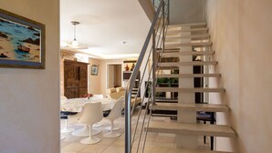Un interior moderno con una escalera, comedor y un cuadro en la pared.
