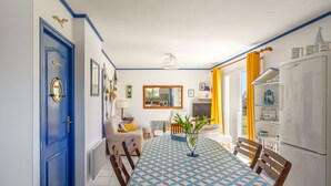 Ein Essbereich mit einer blau-weißen Tischdecke, einer blauen Tür und einem weißen Kühlschrank.
