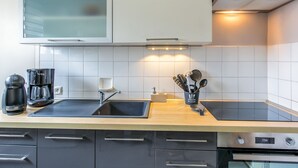 Een moderne keuken met een roestvrijstalen spoelbak, een koffiezetapparaat en een afzuigkap.