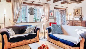 A cozy living room with two sofas, a coffee table with fruit, and a stone wall. - Dolce Vita by Interhome (Plouha)