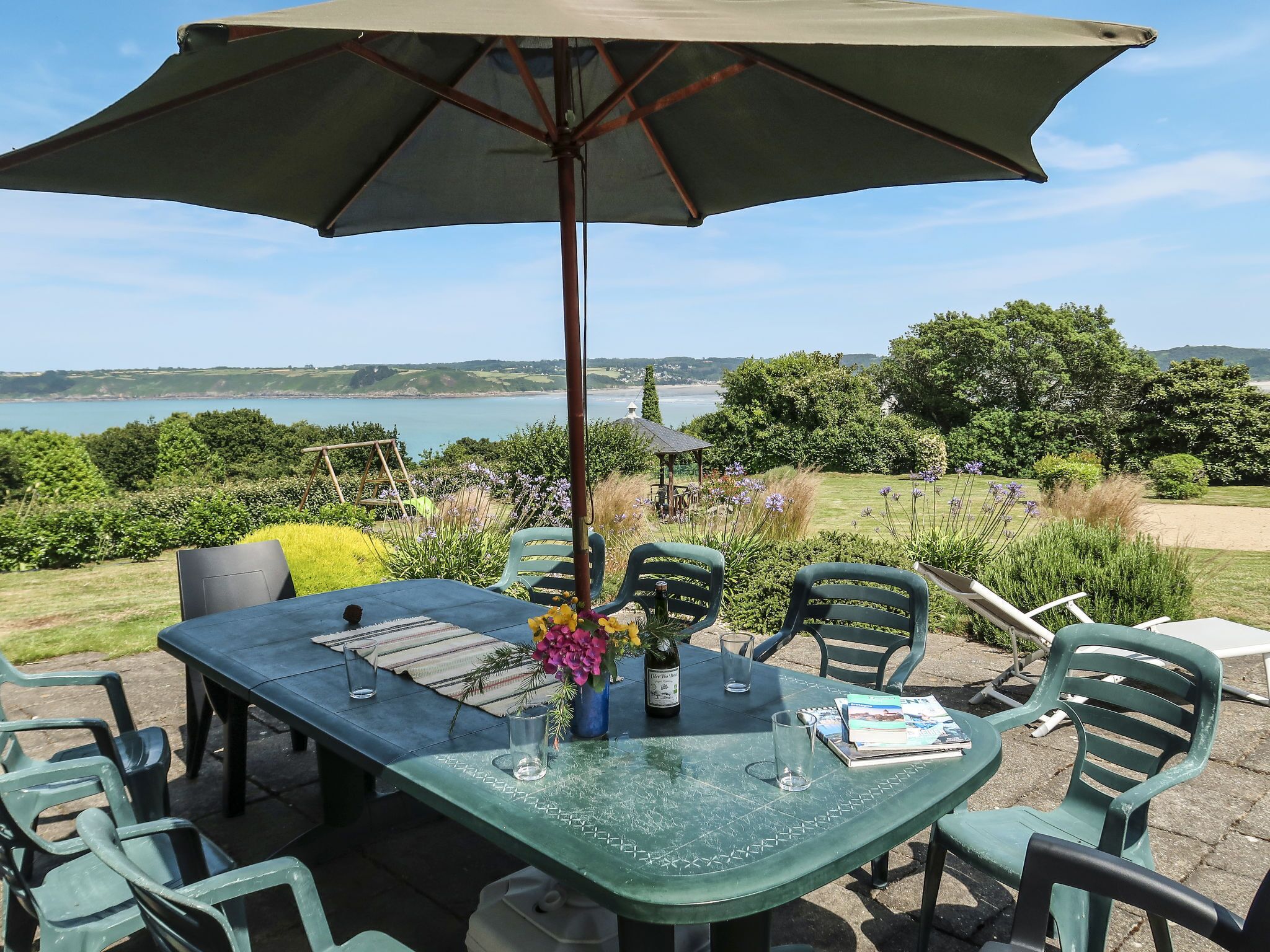 A table set outdoors with a view of the sea and hills.