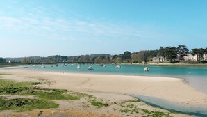 A coastal scene with a sandy beach, boats on calm waters, and buildings in the background. - Ker Svea by Interhome (Plestin les Greves)
