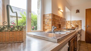 A modern kitchen with a large window, a built-in sink, and wooden cabinetry. - Pors Ar Goff by Interhome (Plestin les Greves)