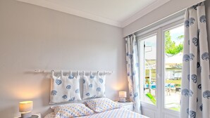 A bedroom with a bed, two bedside tables, a window with curtains, and a view of the outside. - Chante-Brise by Interhome (Plérin)