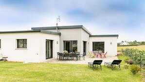 A modern two-story house with a patio area featuring outdoor furniture and a garden. - Terre et Mer by Interhome (Treflez)