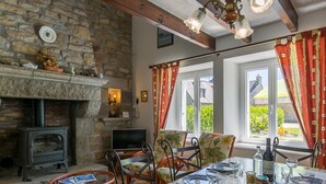 Un coin repas chaleureux avec une cheminée en pierre, des poutres en bois et une table dressée pour le repas.