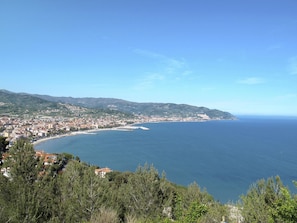 Uma cidade costeira com praia, colinas e céu claro.