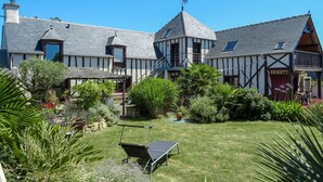 A traditional half-timbered house with a thatched-roof structure, a well-maintained garden, and a clear blue sky. - Valhalla, chez Jules by Interhome (Planguenoual)