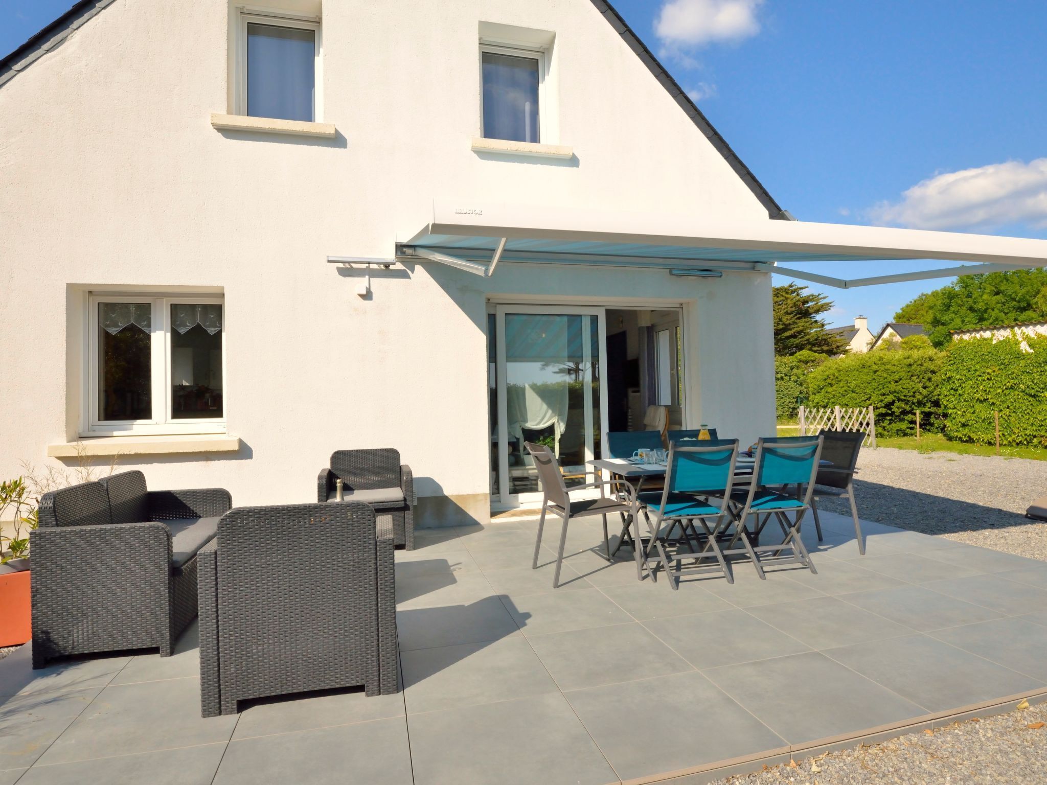 Une maison blanche dotée d’un patio couvert, aménagé avec du mobilier d’extérieur et une table.