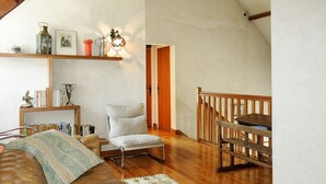 A cozy living room with a leather sofa, a wooden chair, a bookshelf, and a staircase. - Stergann by Interhome (Mesquer/Quimiac/Kercabellec)